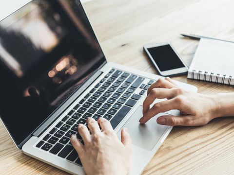 Hände berühren die Tastatur eines Laptops