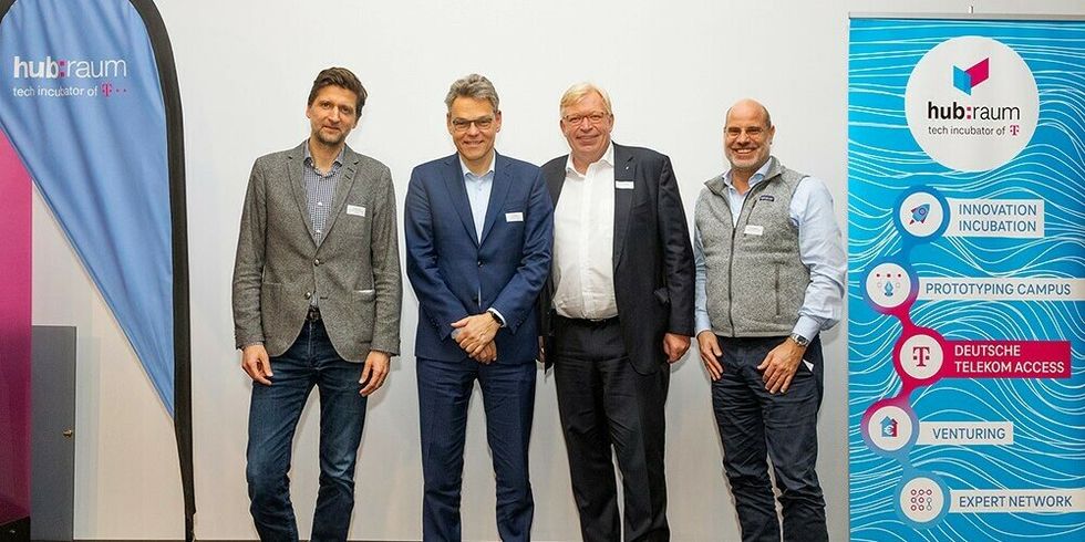 Vier Männer stehen nebeneinander. Neben ihnen steht ein Aufsteller mit dem Logo des hubraum.