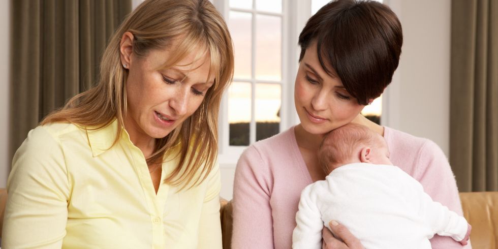 Eine Hebamme spricht mit einer Mutter, die ihr Kind im Arm hält