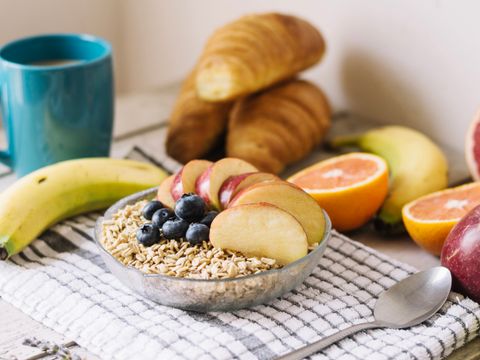 Fotografie von einem gedeckten Frühstückstisch mit Müsli, Croissants, Früchten und Kaffeetasse.