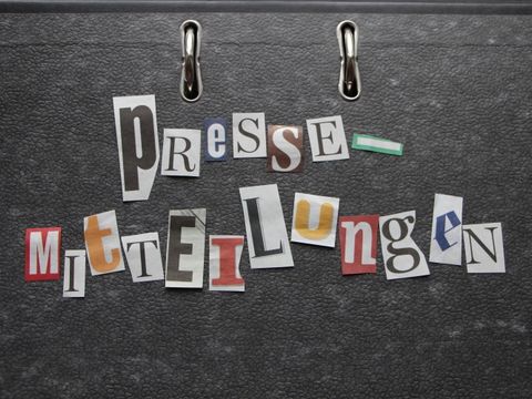 ausgeschnittene Zeitungsbuchtagen bilden das Wort Pressemitteilungen