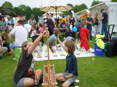 Klein und Groß beim Spielen auf der Wiese des Festgeländes