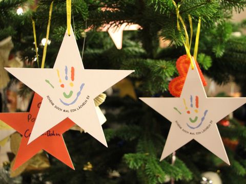 Mehrere Wunsch-Sterne von "Schenk doch mal ein Lächeln e.V." am Wunschbaum im Foyer des Rathauses Schöneberg