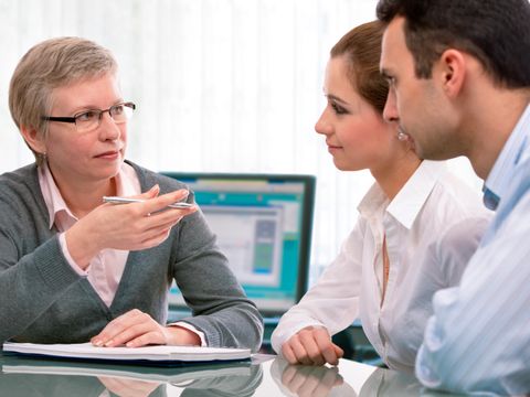 Zwei Personen im Gespräch mit einer Frau am Besprechungstisch