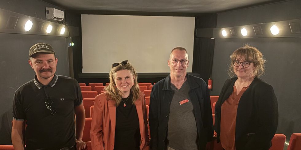Vier Personen stehen in einem kleinen Kinosaal mit roten Stühlen vor einer weißen Leinwand. Von links nach rechts: Manuel Godehardt vom Kino Intimes, Bezirksbürgermeisterin Clara Herrmann, Frank Hüpperling (FKU-Vorstand) und Kathrin Klisch von der Wirtschaftsförderung des Bezirksamts Friedrichshain-Kreuzberg. Alle blicken freundlich in die Kamera, das Licht im Saal ist gedimmt, aber die Gesichter sind gut zu erkennen.