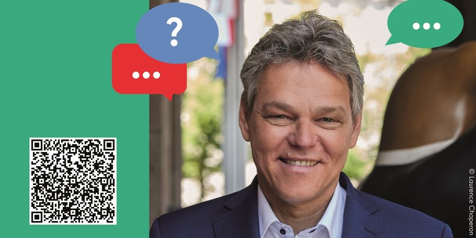 Ein Mann steht vor einem Gebäude und lächelt. Vom Mann ausgehend sind bunte Sprechblasen eingefügt.