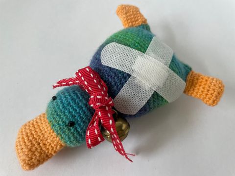 eine Stofftier-Ente mit zwei Pflastern