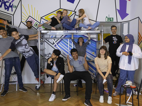 Jugendliche neben und auf einem Gerüst ist einem bunt gestaltetem Raum.