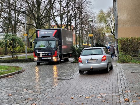 LKW auf schmaler Straße, PKW hält auf Gehweg