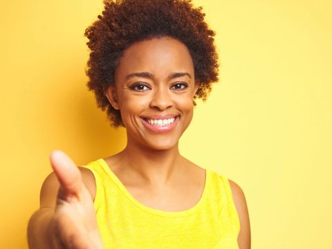 Lächelnde Frau streckt die Hand entgegen