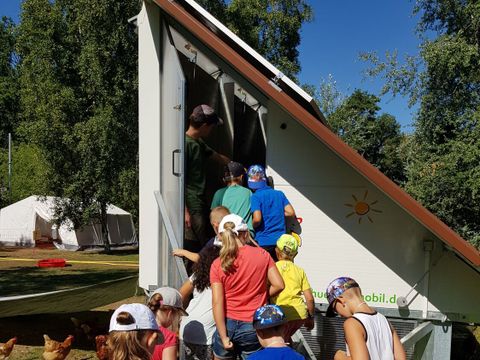 mehrere Kinder und Hühner vor dem mobilen Hühnerstall