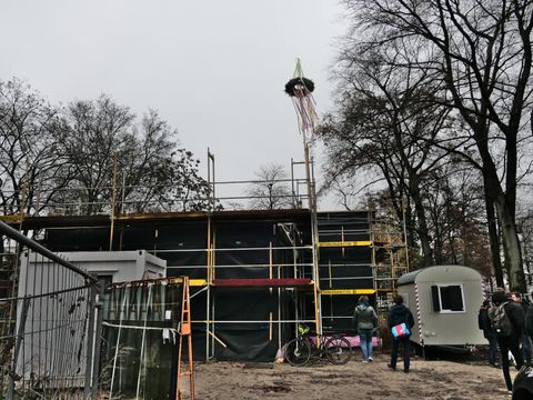 Der eingerüstete und abgedeckte Rohbau des neuen Spielhauses mit dem Richtkranz