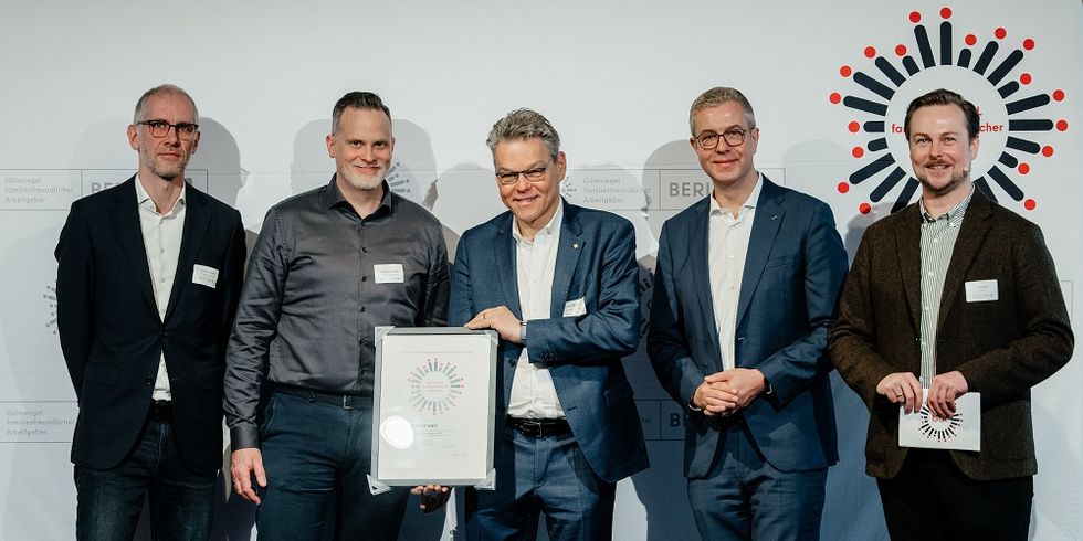 5 Männer lächeln in die Kamera, einer hält eine Urkunde in der Hand