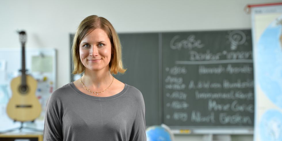 Lehrerin steht im Klassenzimmer vor einer Tafel