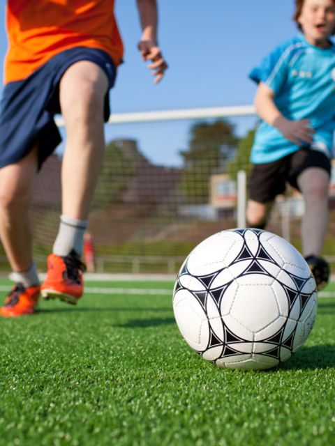 Jungs spielen Fußball auf Feld