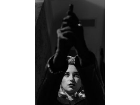 Gesicht einer Frau, die eine Pistole in den Händen über dem Kopf hällt