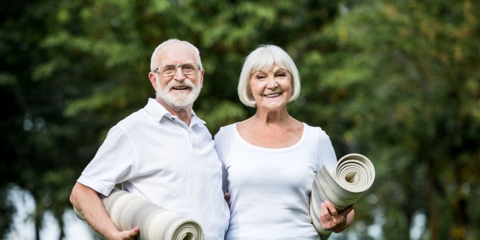 älteres Paar mit Yogamatten unter den Armen