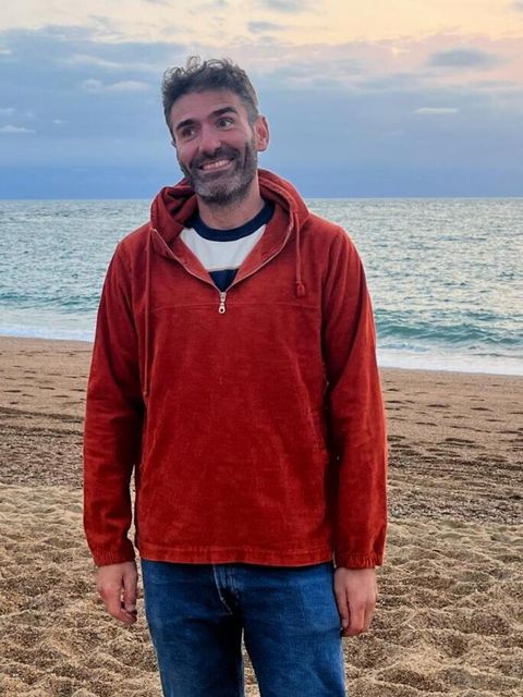 Der Kursleiter Floran Bayle der Französisch an den Berliner vhs lehrt am Strand mit dem Meer im Hintergrund