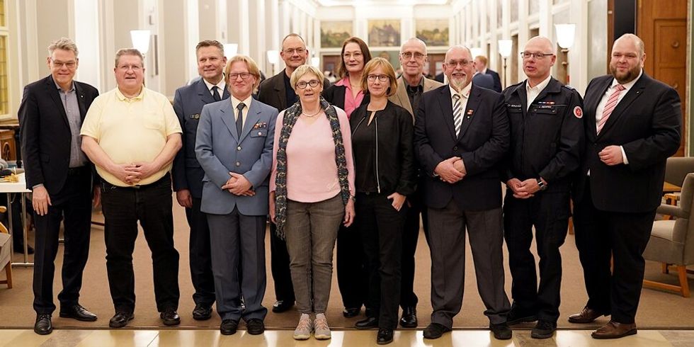 Gruppenbild mit mehreren Personen, die in einer langen repräsentativen Halle stehen