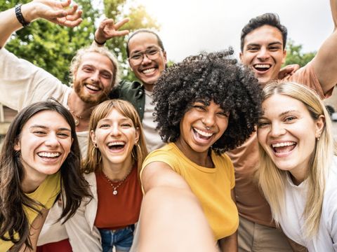 Multikulturelle Freunde, die draußen gemeinsam in die Kamera lächeln