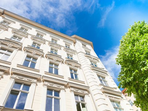Fassade eines Berliner Altbaus, davor steht ein Baum