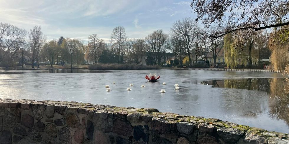 Auf einem Teich sind künstliche Seerosen verteilt.