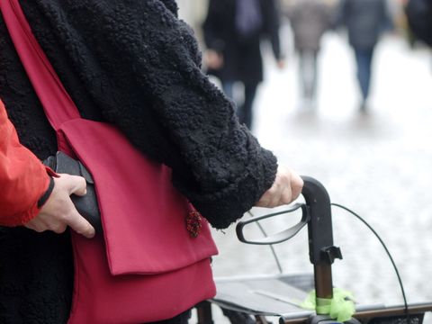 Ein Dieb zieht ein Portemonnaie aus einer Handtasche