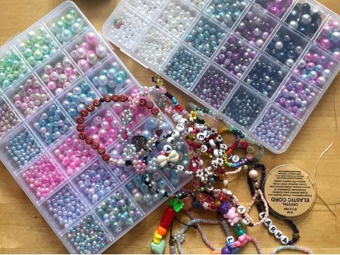 Blick auf Sortierkästen mit verschiedenen Perlen und darauf liegend ein paar Ketten