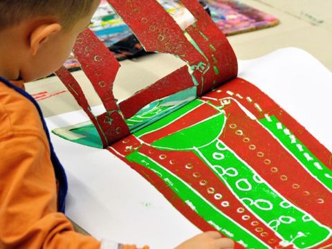 Werkstatt Kunterbunt: Ein Kind zieht eine Schablone vom bedruckten Papier ab.