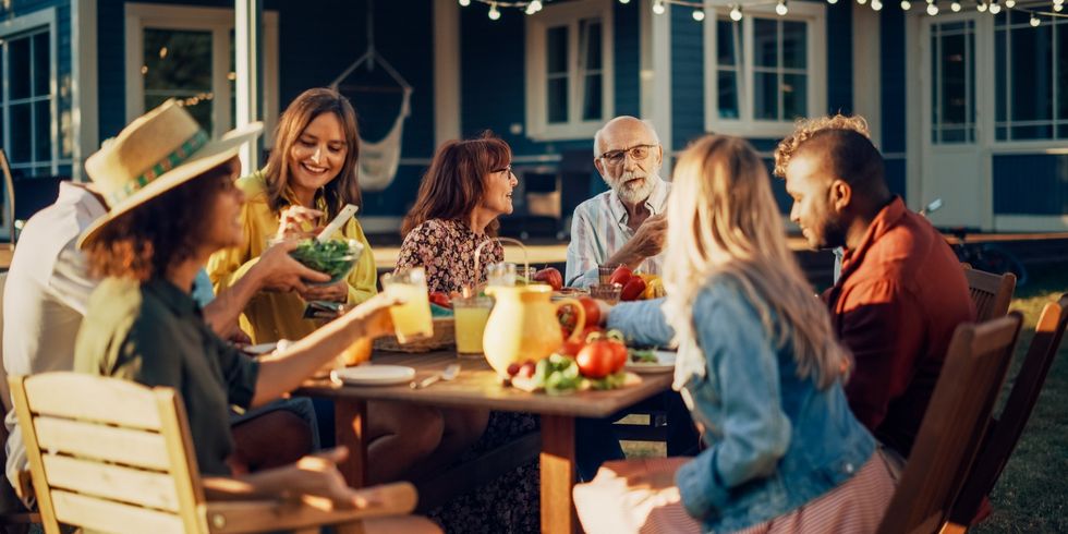 Eltern, Kinder und Freunde versammelten sich an einem Grilltisch vor einem schönen Haus. Menschen unterschiedlicher Herkunft, Jung und Alt, hatten Spaß, aßen und tranken. Eine Gartenparty im Hinterhof.
