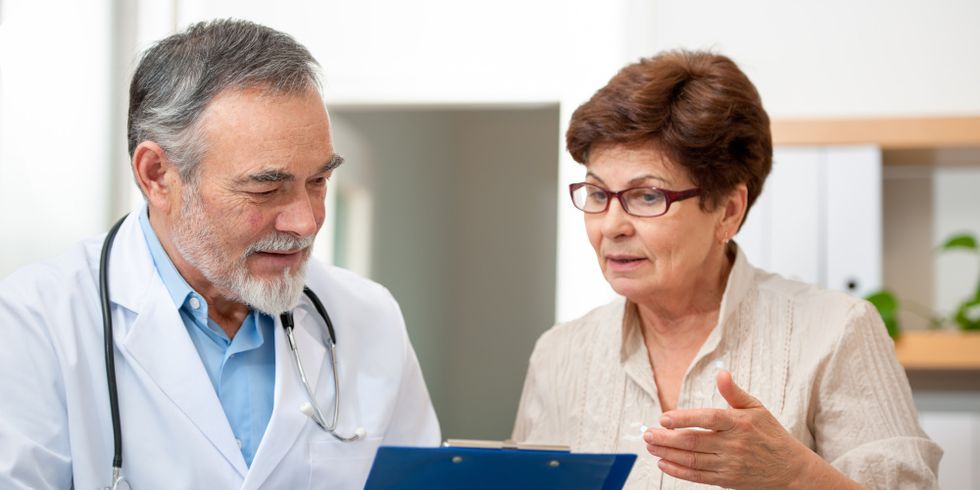 Eine Patientin diskutiert mit ihrem Arzt das Schreiben, welches der Arzt in der Hand hält
