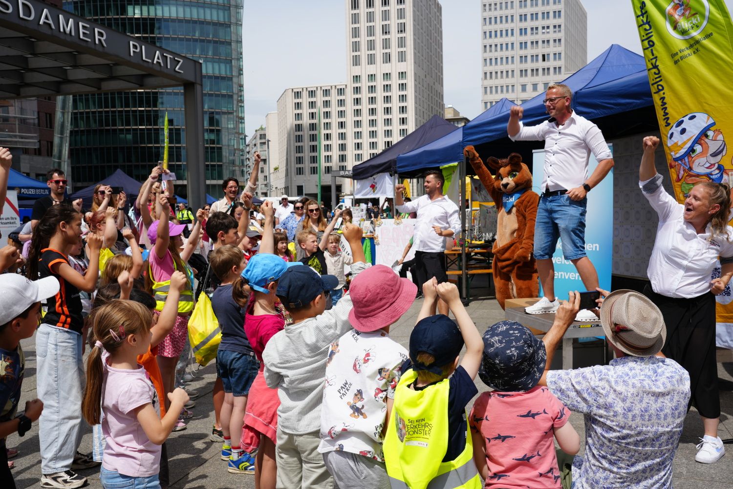 Kinder stehen vor einer Bühne, während Personen darauf performen