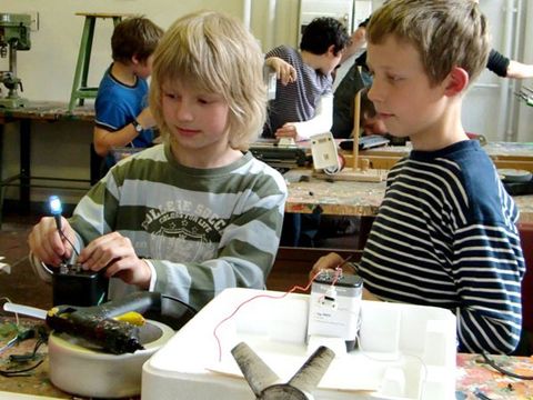 Bauwerkstatt Maschinen: Zwei Kinder bauen mit einer Batterie ein Leuchtobjekt.