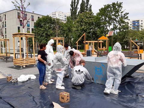 Kinder und Jugendliche in Schutzanzügen an einer grauen Tischtennisplatte