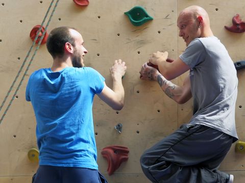 Zwei junge Männer an der Kletterwand in einer Halle