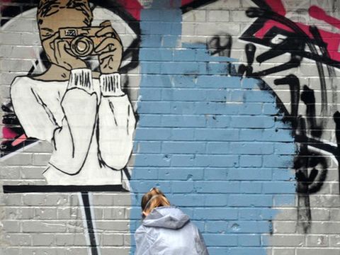 Streetart: Kind in Schutzanzug arbeitet vor einer Wand mit Paste Up und Graffiti. (Bild: © Jugendkunstschule Pankow)