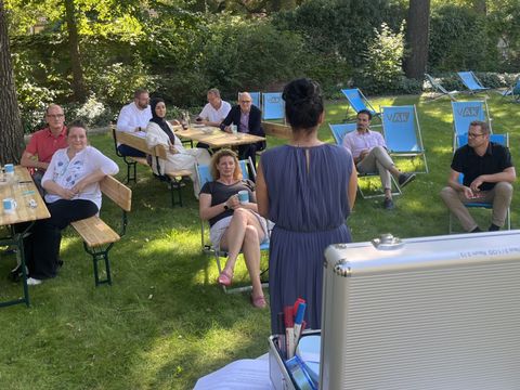 Teilnehmende auf Liegestühlen hören einer sprechenden Person zu