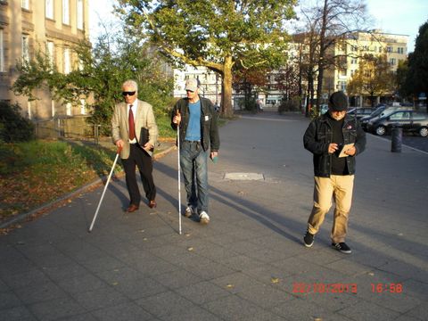 drei Männer laufen auf der Straße, zwei davon mit Krücken.