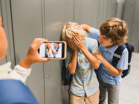 Schüler filmen mit dem Handy, wie sie ihren Mitschüler in der Schule schikanieren.