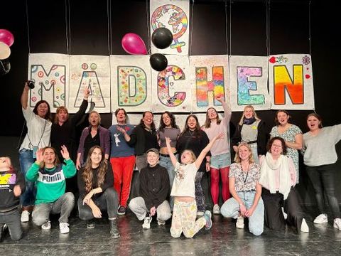 Eine Gruppe von Mädchen hält ein zusammengesetztes Schild mit dem Wort Mädchen hoch