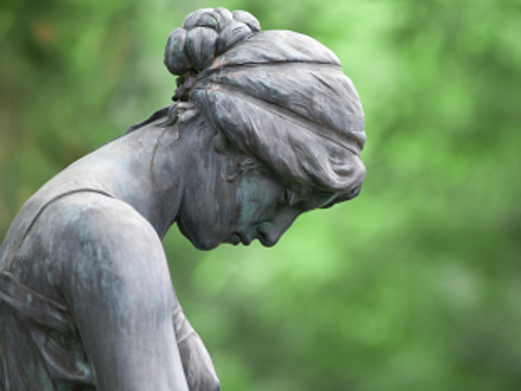 Frauenstatue aus Stein auf einem Friedhof