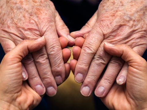 Die Hände einer Frau spenden Kraft und Trost, und die eines älteren Herrn