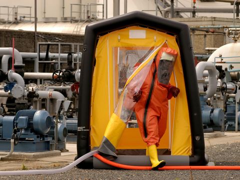 Person in Schutzanzug verlässt ein Dekontaminationszelt