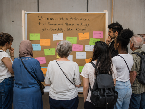 Personen stehen vor einer Pinnwand zum Thema Was muss sich in Berlin ändern, damit Frauen und Männer gleichberechtigt leben können?