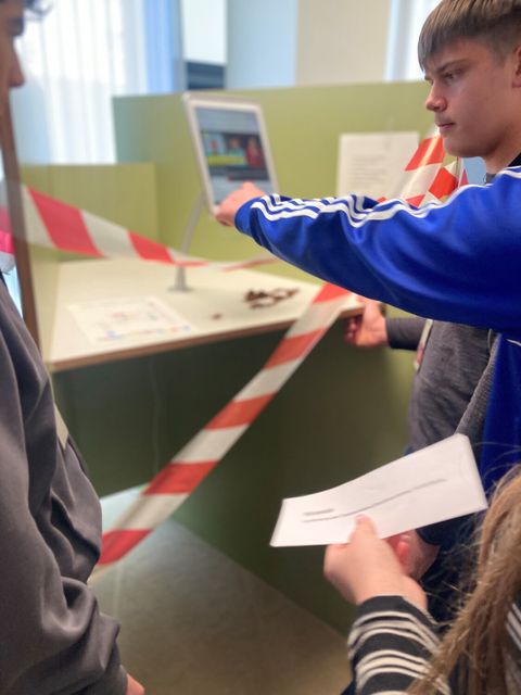 Jugendliche lösen ein Rätsel am Kundenterminal.
