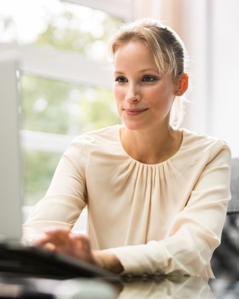 Eine junge Frau arbeitet in einem Büro am Bildschirm