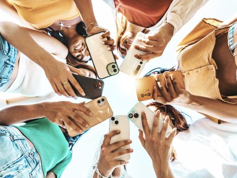 Gruppe junger Menschen, die draußen ein intelligentes Mobiltelefongerät benutzen, heller, farbenfroher Filter