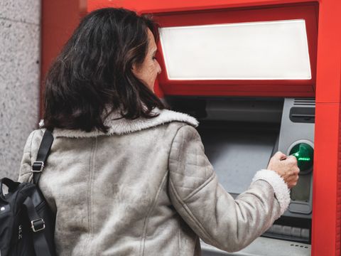 Frau an Bankautomaten zieht Geld ab