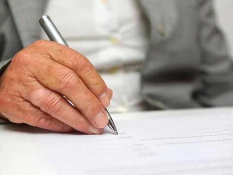Ältere Frau, die ein Dokument signiert