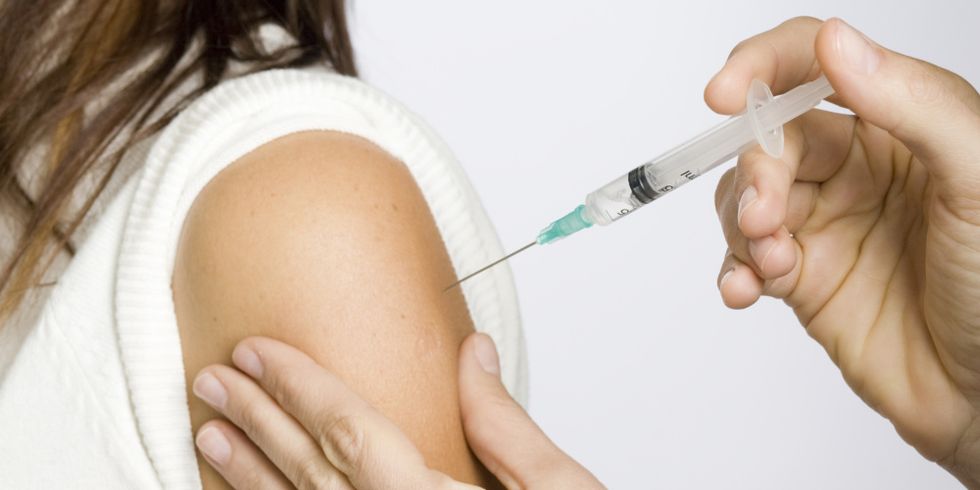 Einer Frau wird eine Spritze in den Arm verabreicht